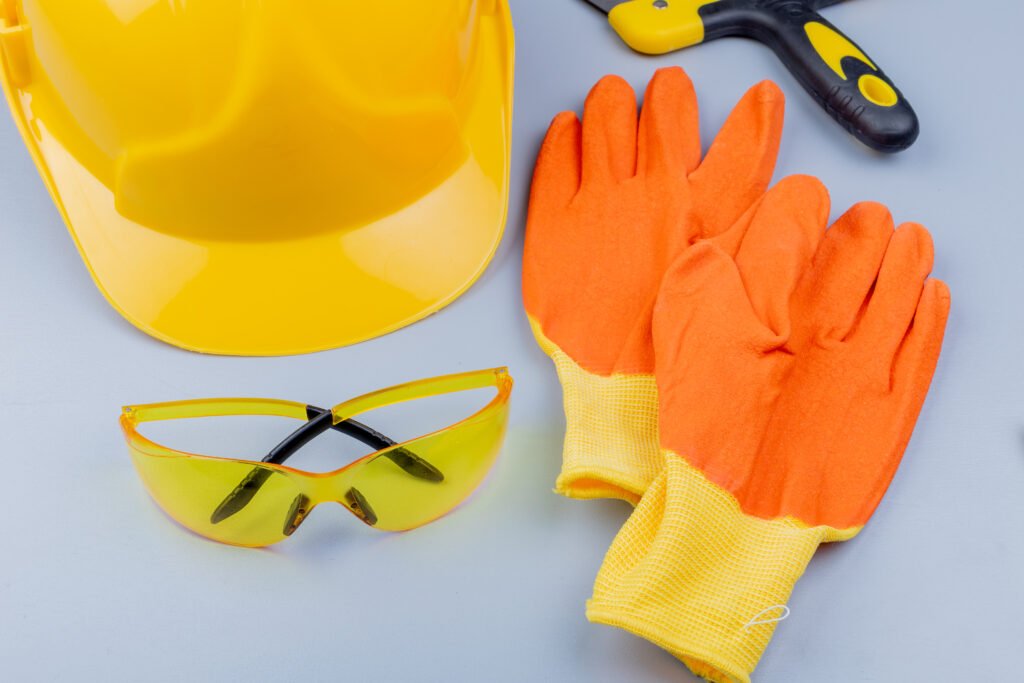 close up view of pattern from set of construction tools as safety glasses safety helmet putty knife and gloves on gray background